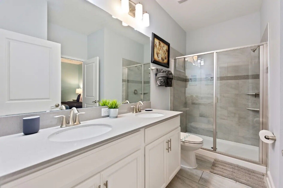 A bathroom with two sinks and a walk in shower.